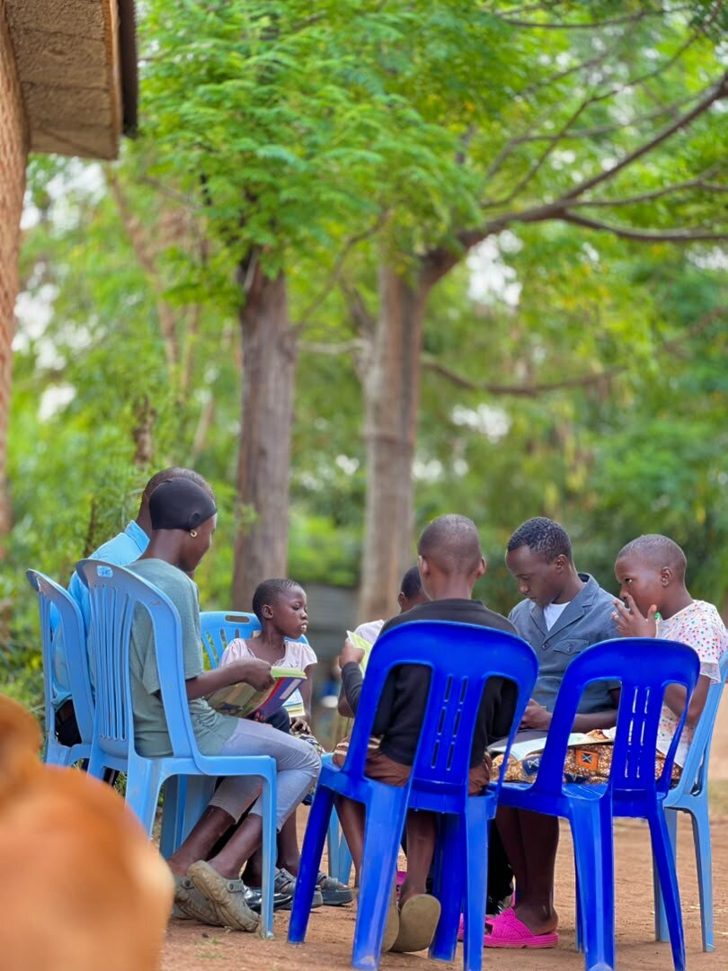 An outdoor Bible study circle seated under the trees